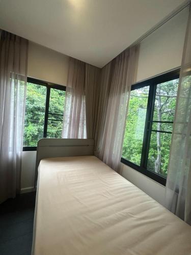 a bedroom with a bed and two windows at K5 Seaview Hillside 3BR and 1 Staff Quarter in Ban Ko Kok
