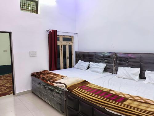 NaimishāranyaMa vindhyavasini Atithi Bhavan的一间卧室配有两张带白色床单和镜子的床