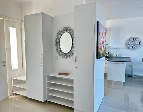 a white kitchen with a sink and a mirror at Modern Poolside Apartment in Sun Valley in Ayios Yeoryios