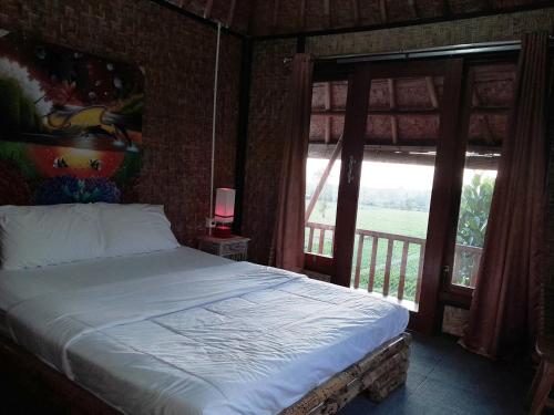 a bedroom with a bed and a large window at D'Tebe House Kelating in Tabanan