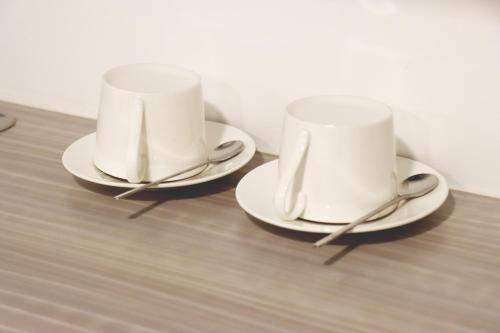 two white cups and saucers sitting on a table at UTD8 Hotel and Residence in Bangkok