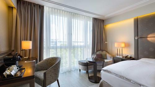 a hotel room with a bed and a desk and a chair at Pullman Munich in Munich