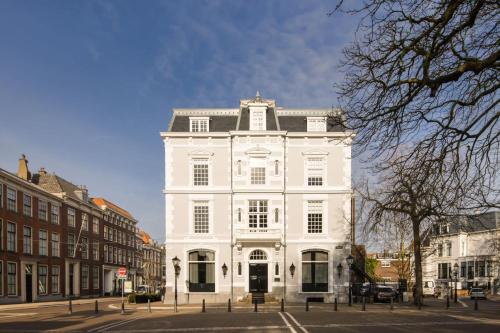 een groot wit gebouw aan een stadsstraat bij ADAM & EVE Paleisstraat in Den Haag
