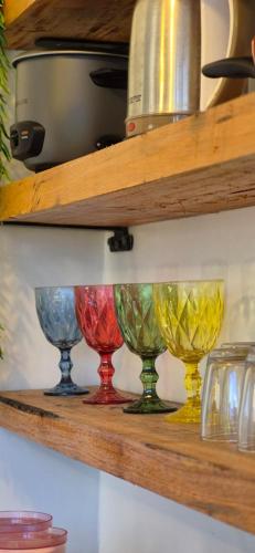 Una fila de copas de vino de colores en un estante. en GBoy Guest House, en General Luna