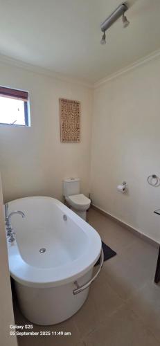 un bagno bianco con vasca e WC di Cape Town Penthouse On the Atlantic Ocean! a Hout Bay