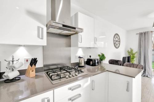a kitchen with white cabinets and a stove top oven at Foxherne 6BDR 3BA Serviced House with Parking - Slough By 360Stays in Slough