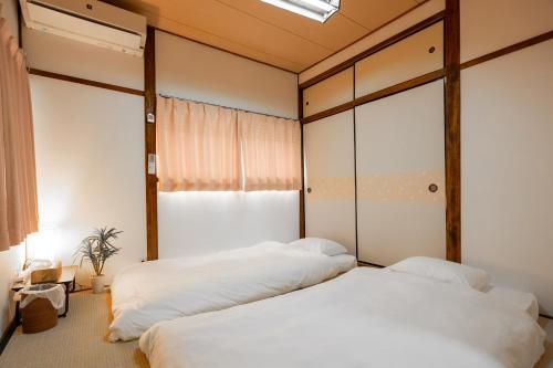 a bedroom with two beds and a window at Jikka Japan in Izumi-Sano