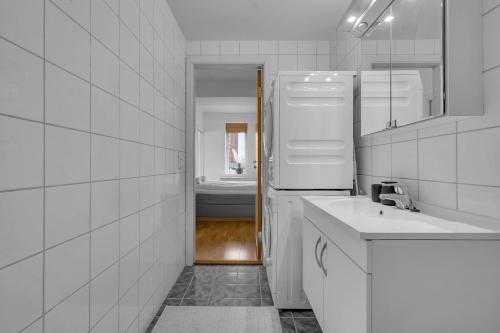 a white bathroom with a sink and a refrigerator at Centrally located apartment in Tromsø in Tromsø