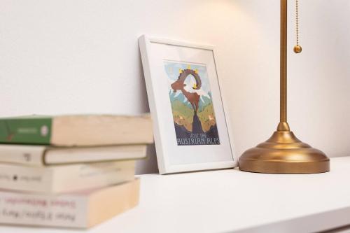 a desk with a lamp and a picture and books at Apartments C'EST LA SEA - Whirlpool-Suite oder Dachterrassen-Suite in Neusiedl am See