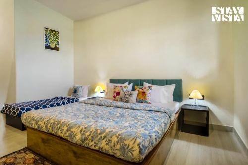 1 dormitorio con 2 camas con almohadas y 2 lámparas en StayVista at Thalassa Near The Beach, en Alibaug