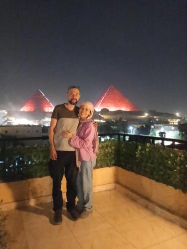 a man and a woman standing on a balcony at night at The Pyramids Crypt Inn in Cairo