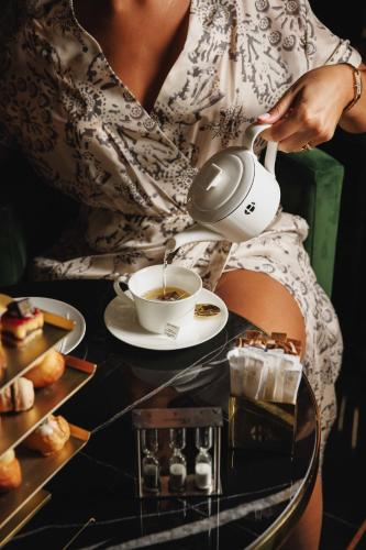 Una donna sta versando il caffè in una tazza di Bra Hotel a Bari