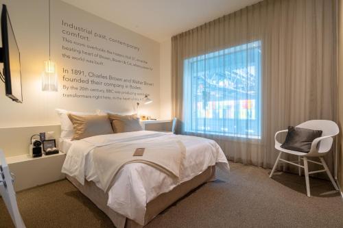 a bedroom with a bed and a window and a chair at Trafo Hotel Baden in Baden