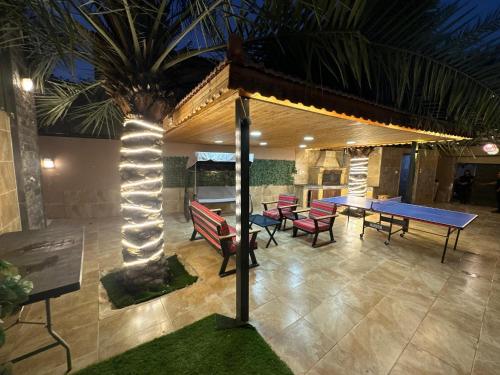 a patio with a table and chairs and a palm tree at Al Zain Chalet - Private Pool in Al Kafrayn