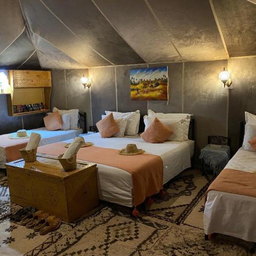 a bedroom with two beds in a tent at Aurum Dunes Luxury Camp in Merzouga