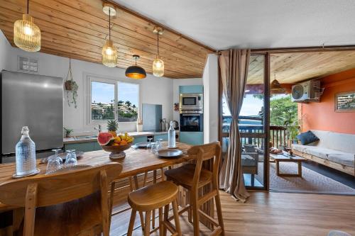 Il dispose d'une cuisine et d'un salon avec une table et des chaises en bois. dans l'établissement Sunset Léla Saint Gilles apparemment t 3 avec terrasse vue port et mer, à Saint-Paul