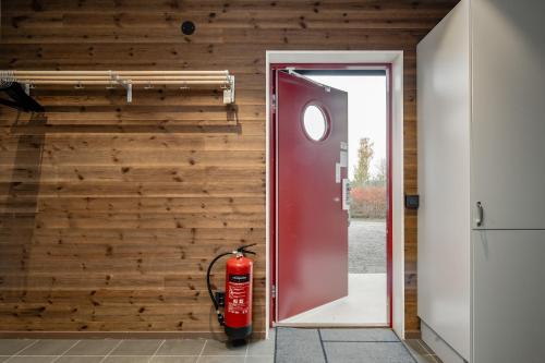 a red door with a fire hydrant next to a wall at Bergsgården Lodge Järvsö - Ski In Ski Out med bastu invid Järvsöbacken - OBS!!! BYTESDAGAR ÄR ENDAST TORS O SÖND OBS!!! in Järvsö