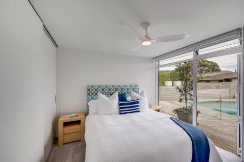 a bedroom with a bed and a balcony with a pool at The Whyte House - Waimarama Beachfront in Waimarama