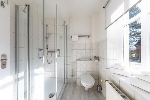 Un baño blanco con inodoro y ducha. en StrandLiebe am Strandbad, en Malchow
