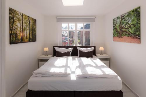 Un dormitorio con una gran cama blanca con dos ventanas. en StrandLiebe am Strandbad, en Malchow