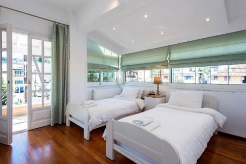 two beds in a room with windows at Kassiopi Home in Kassiopi