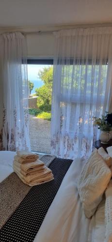 a bed with towels on it with a window at Dinky's Place in Herolds Bay