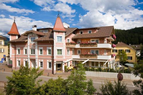 a large pink building with towers on a street at Hotel Blitzburg in Brunico