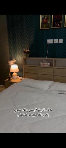 a bedroom with a white bed and a lamp at شقة البشائر in Al Khawḑ