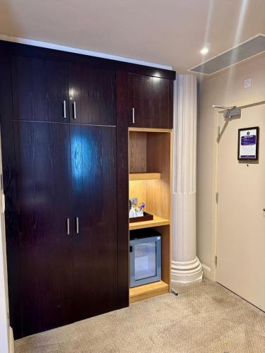 a large wooden cabinet with a microwave in a room at Fenwick Street Hotel by EPIC in Liverpool