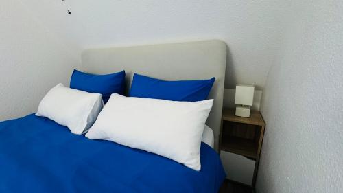 Ferienwohnung Heimathafen في لوبيك: سرير بمخدات زرقاء وبيضاء وموقف ليلي