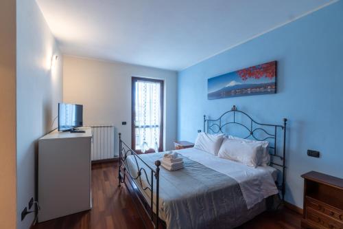 Residenza Prezzemolo في كاستلنوفو ديل جاردا: غرفة نوم زرقاء مع سرير وتلفزيون