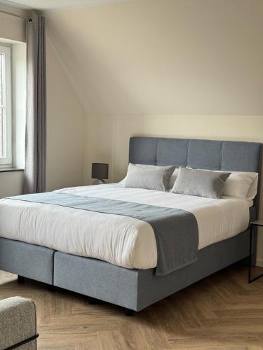 a large bed with a blue headboard in a bedroom at MYROOM am Park in Lohne
