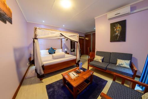 a bedroom with a bed and a couch and a table at 2 Friends Guest House in Jinja