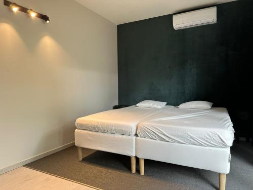 een wit bed in een kamer met een groene muur bij Woodboxcabins - Campinggroenpark in Zele