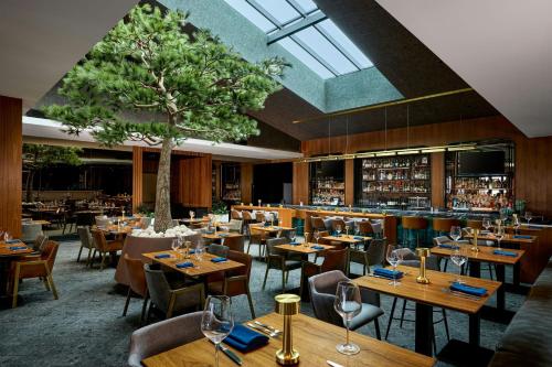 a restaurant with wooden tables and chairs and a tree at VEA Newport Beach, a Marriott Resort & Spa in Newport Beach
