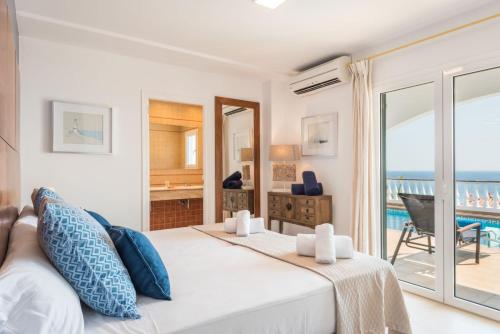 a bedroom with a bed and a view of the ocean at Villa del Mar by Menorca Vacations in Son Bou