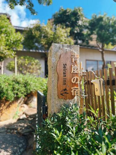 a sign on a rock in front of a fence at Okayama Garden House Near Station Free Parking in Okayama