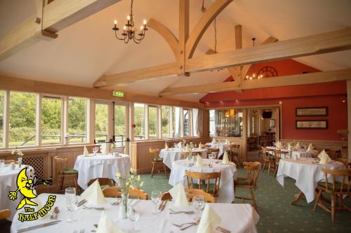 a restaurant with white tables and chairs and windows at The Half Moon in Petersfield