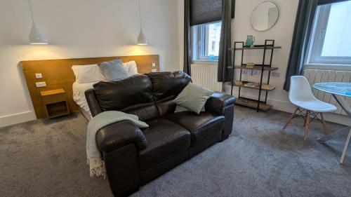 Una sala de estar con un sofá de cuero y una mesa. en Captivating 1-Bed apartment Merthyr Tydfil -, en Merthyr Tydfil