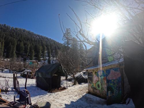 een zon die schijnt op een tent in de sneeuw bij Cliff Seek in Kalgha