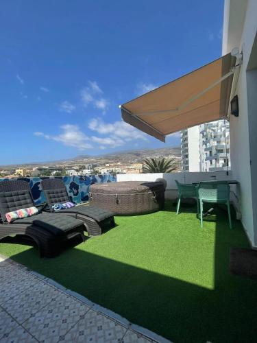 a rooftop patio with chairs and a large umbrella at Playa Paraiso Seaview in Adeje