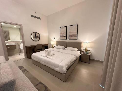 a bedroom with a large white bed and a bathroom at HARF310 Modern Studio w Balcony at Yas Island in Abu Dhabi