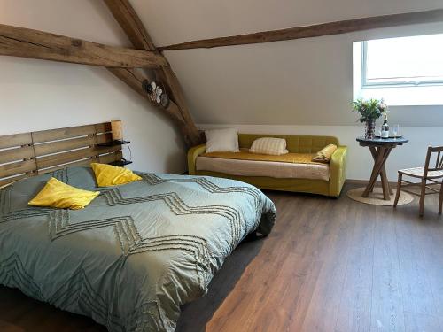 a bedroom with a bed and a couch in a room at Au clos des sens in Demigny