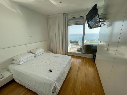 a bedroom with a bed and a tv and a window at Netanya Dream Luxury Apartment MIGDAL DAVID in Netanya