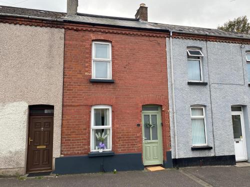 a brick house with a green door and windows at Mercer House in Lisburn