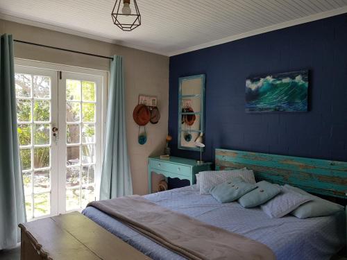 a bedroom with a large bed with a blue wall at Glen Valley Cottage in Glencairn