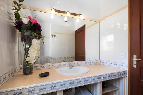 a bathroom with a sink and a vase of flowers at Au Paradis Des Hotes - Chambre Ile in Fouras