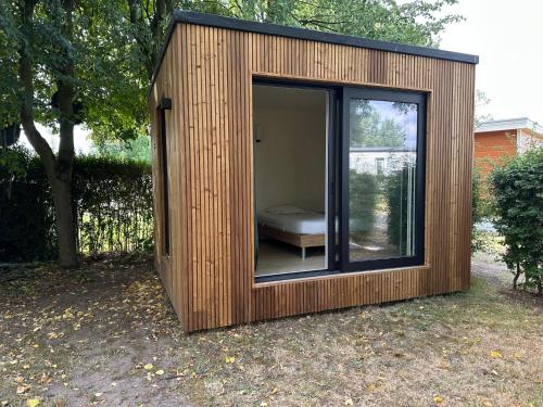 een houten schuur met daarin een bank bij Woodboxcabins - Campinggroenpark in Zele