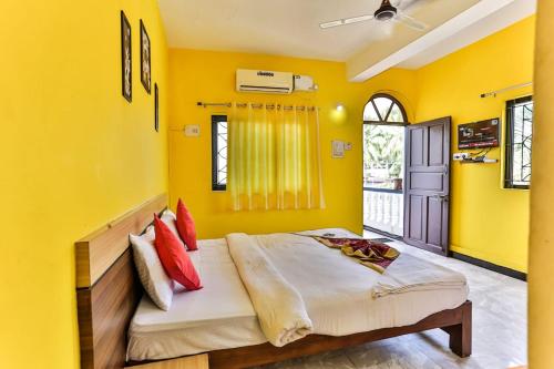 a bedroom with yellow walls and a bed with red pillows at Antonio's hotel in Calangute