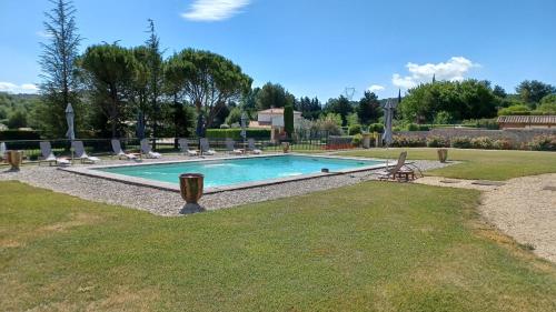 a swimming pool in a yard with chairs around it at La Milane in Cabriès